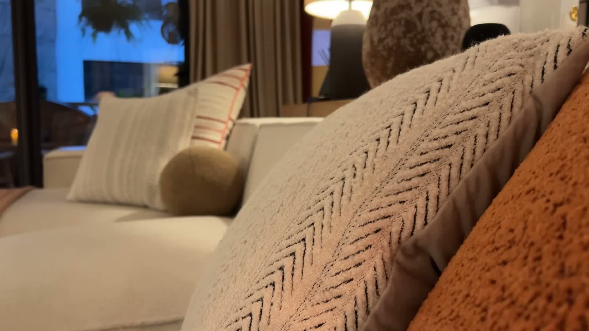 Cream herringbone knit pillow against the rust boucle, up close