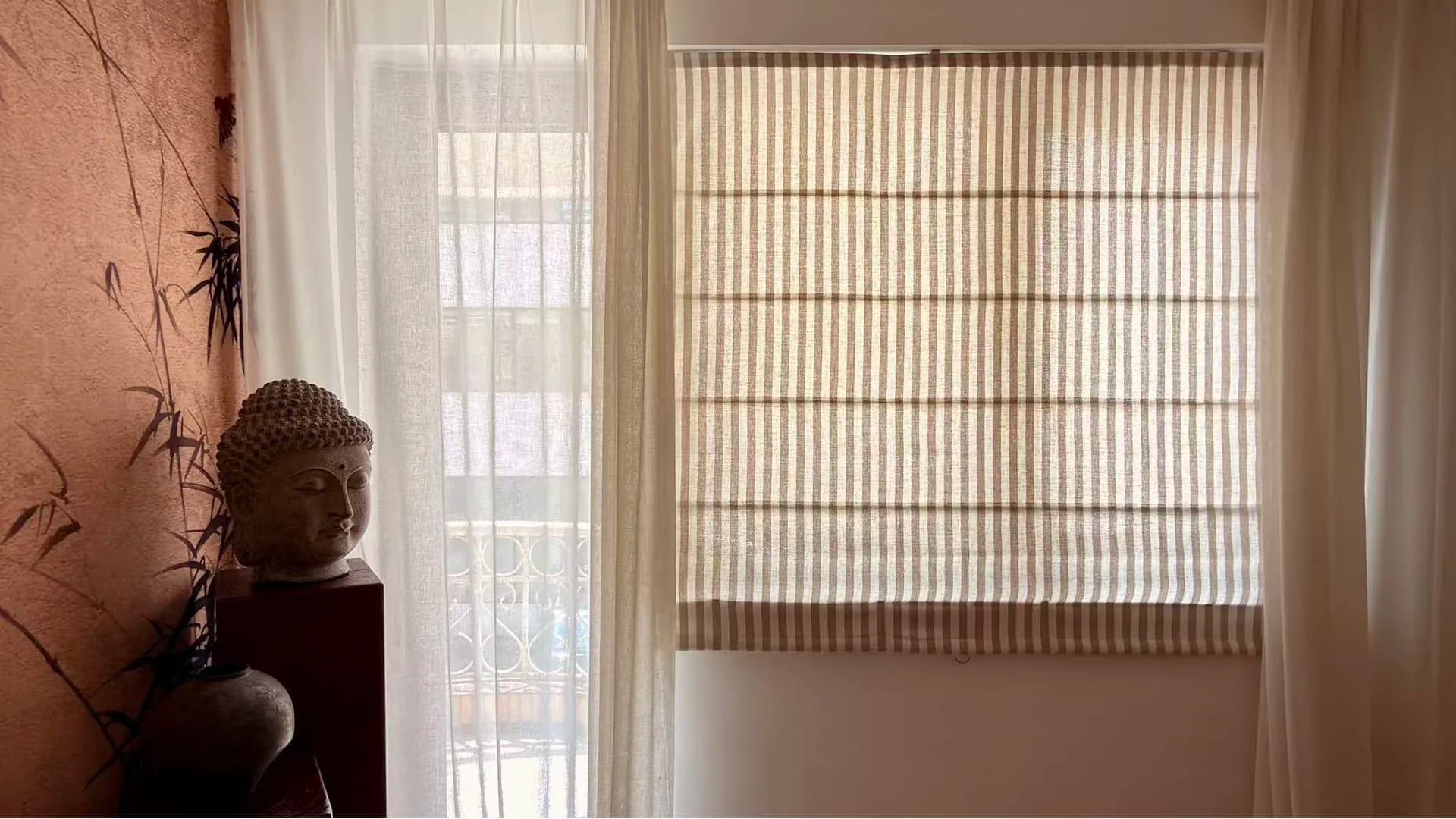 The striped linen roman shade sitting flat in the window, sheers drawn either side
