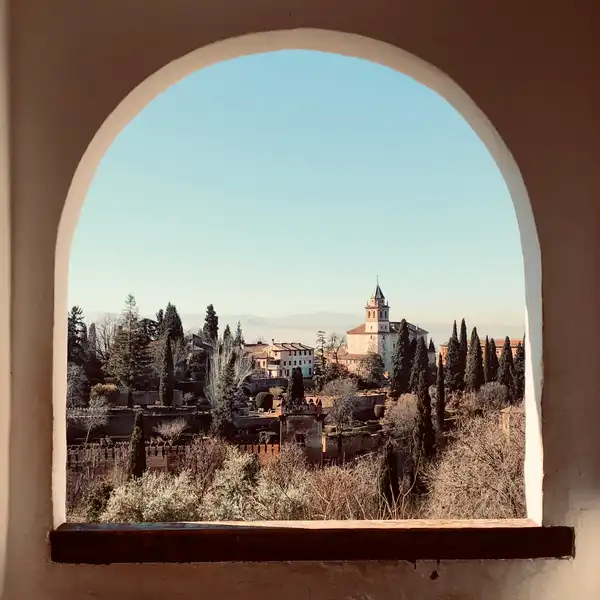 A Spanish palace and gardens seen through a rounded archway