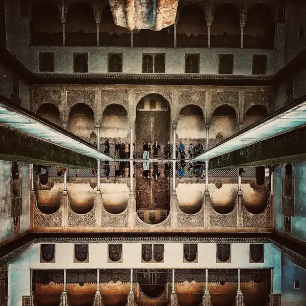 An ornate Spanish courtyard with arched galleries reflected in a still pool